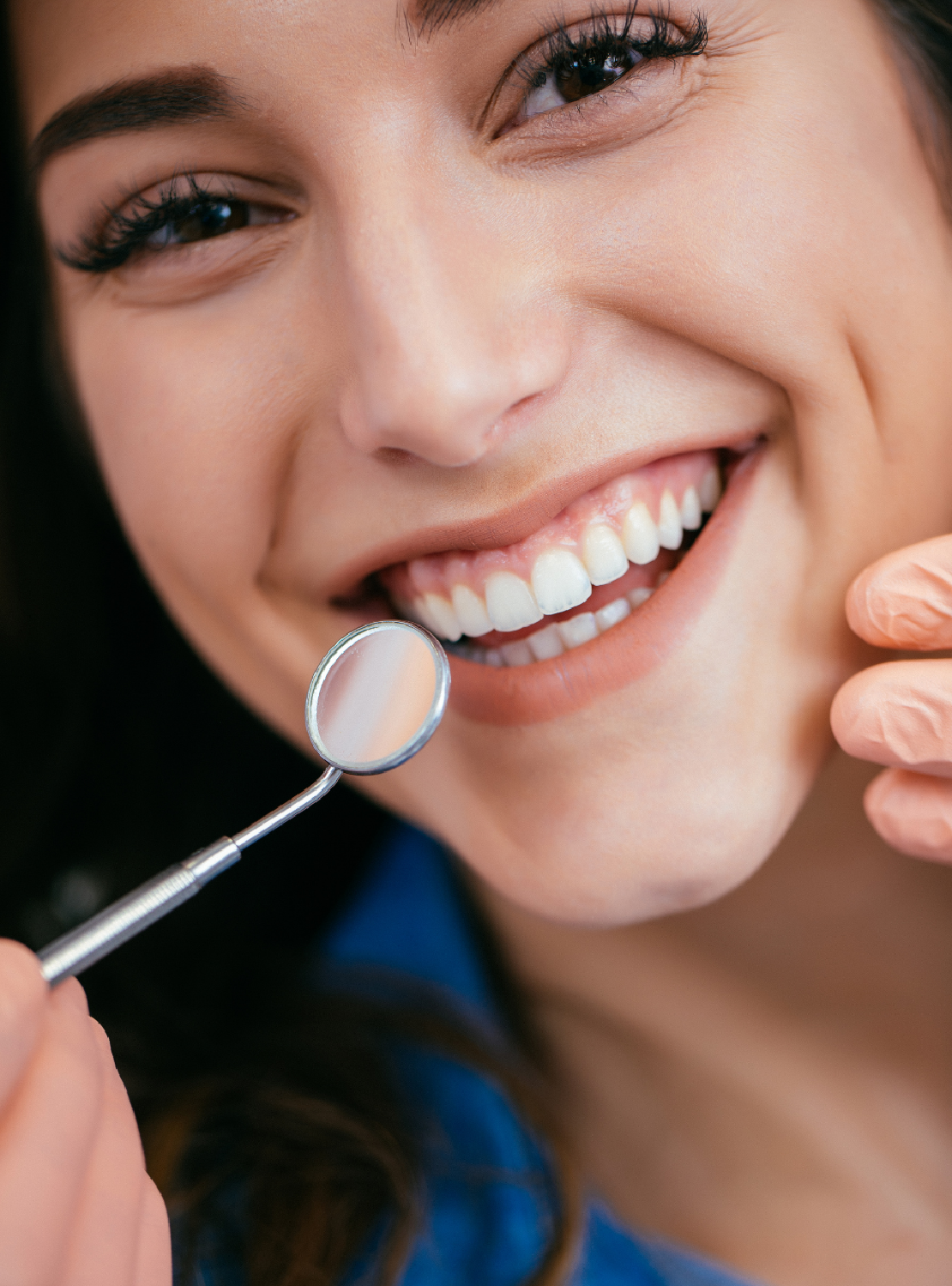 A woman with a bright smile has a dental tool held in front of her after her teeth were examined, highlighting oral care.